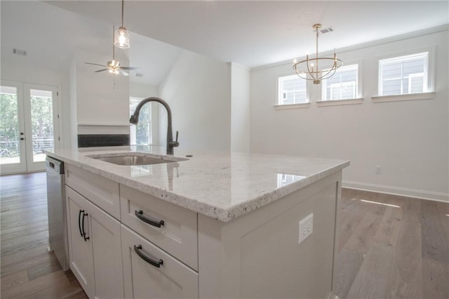 kitchen with sink, ceiling fan with notable chandelier, an island with sink, and light wood-type flooring