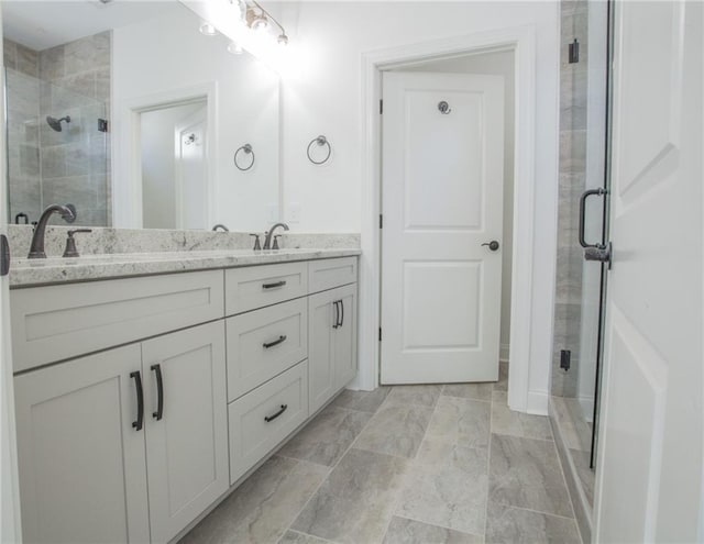 bathroom with a shower with shower door, vanity, and tile patterned floors