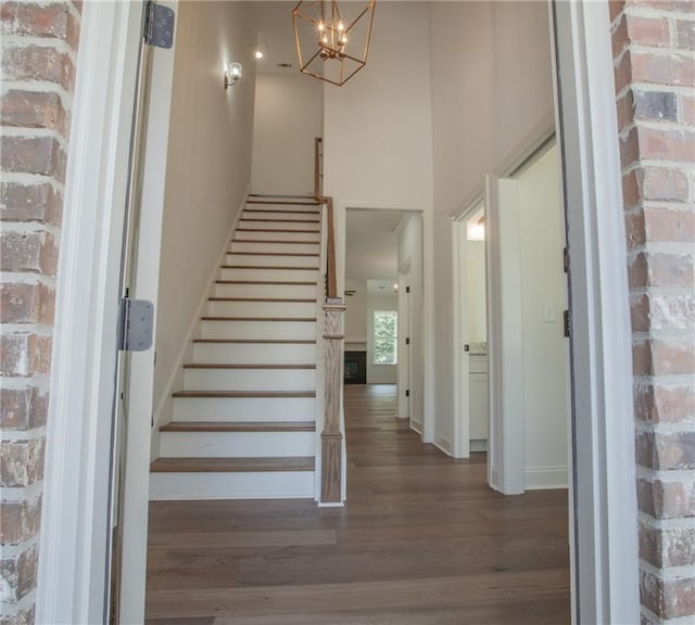 stairway featuring an inviting chandelier, hardwood / wood-style floors, and brick wall