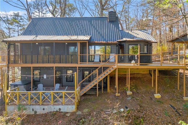 back of property featuring stairway, a sunroom, a chimney, a deck, and metal roof