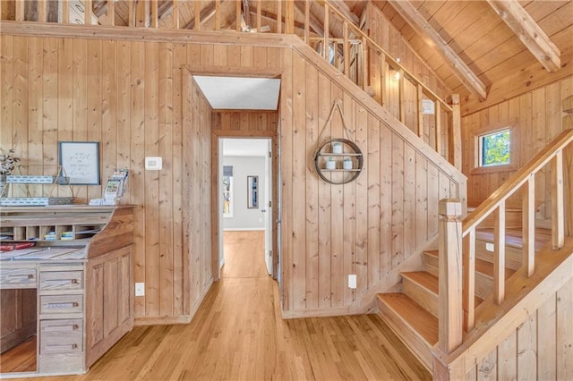 staircase with wood finished floors, baseboards, lofted ceiling with beams, wood ceiling, and wood walls