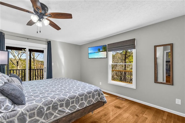 bedroom featuring ceiling fan, baseboards, wood finished floors, a textured ceiling, and access to outside