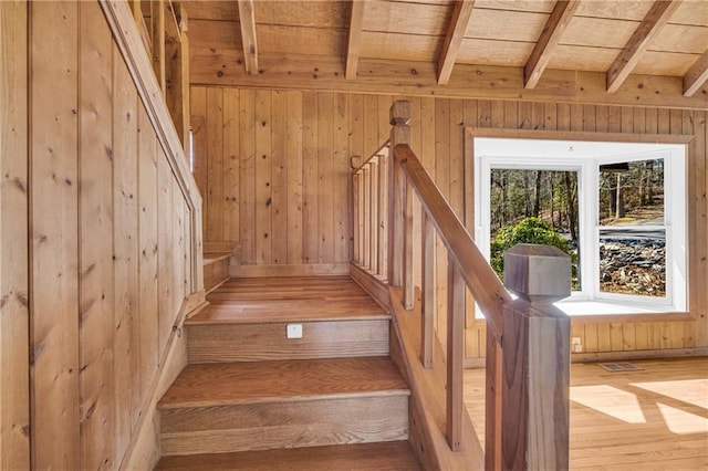 stairway with beamed ceiling, wood walls, visible vents, and hardwood / wood-style flooring