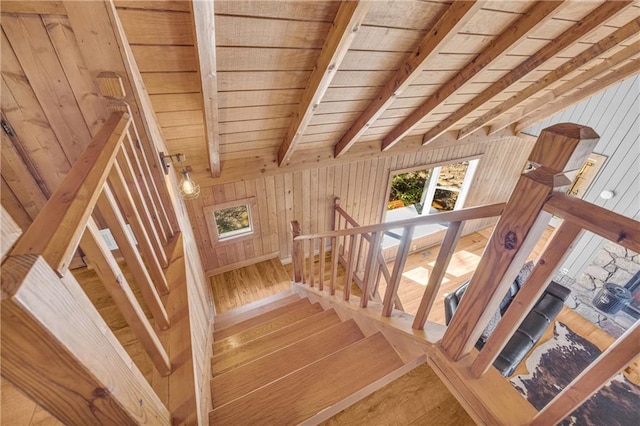 staircase featuring beamed ceiling, wood-type flooring, wood walls, and wooden ceiling