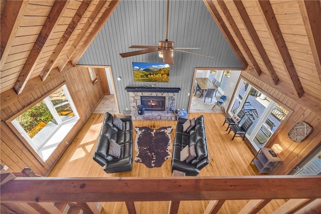 living room featuring beam ceiling, a fireplace, high vaulted ceiling, and wood finished floors