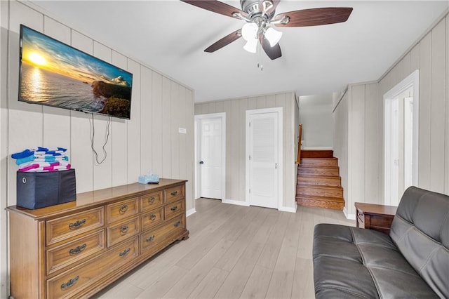 living room with stairway, a ceiling fan, baseboards, and light wood finished floors