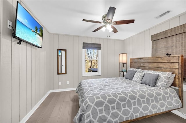 bedroom with visible vents, baseboards, wood finished floors, and a ceiling fan