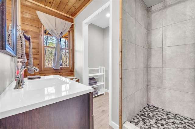 bathroom with a tile shower, vanity, and wood finished floors