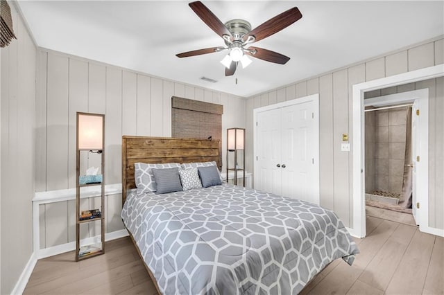 bedroom featuring a ceiling fan, wood finished floors, visible vents, and a closet