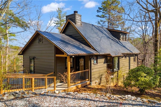 exterior space with metal roof, covered porch, and a chimney