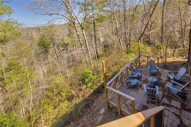 exterior space featuring an outdoor fire pit, a view of trees, and a deck