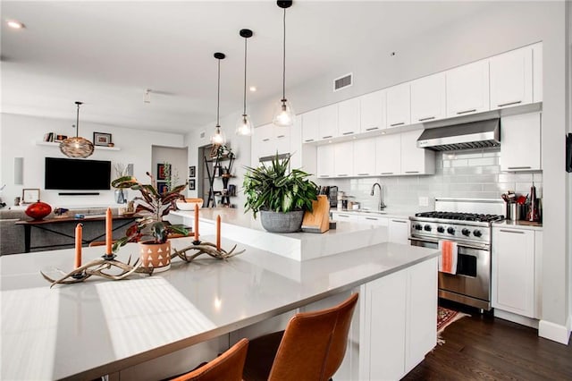 kitchen featuring pendant lighting, white cabinetry, stainless steel range, decorative backsplash, and wall chimney exhaust hood