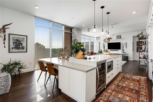 kitchen with stainless steel microwave, hanging light fixtures, a center island, and white cabinets