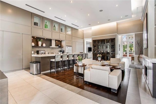 living room with a towering ceiling, tile patterned floors, and french doors