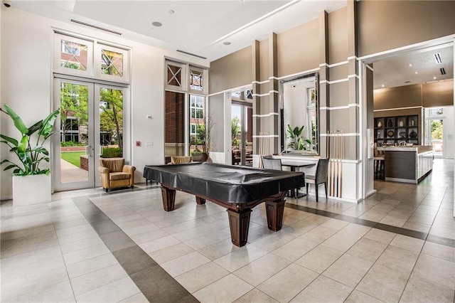 playroom with light tile patterned flooring, a towering ceiling, a healthy amount of sunlight, and french doors