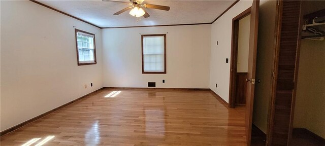 empty room featuring light wood finished floors, a ceiling fan, crown molding, and baseboards