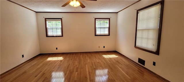 spare room featuring healthy amount of natural light, crown molding, wood-type flooring, a ceiling fan, and a textured ceiling