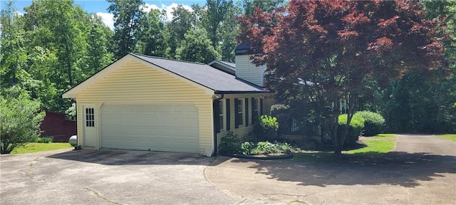 view of home's exterior featuring a chimney and driveway