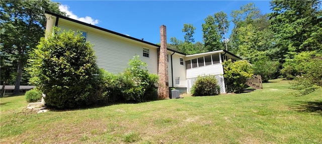 view of property exterior with a lawn, central AC, and a sunroom