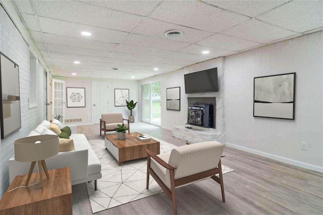 living area with a drop ceiling, wood finished floors, visible vents, and baseboards