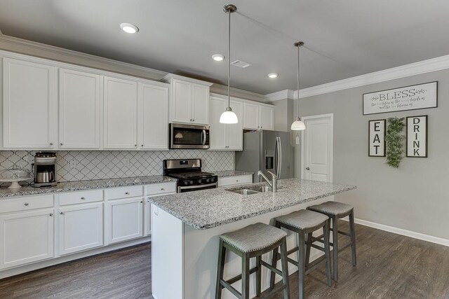 kitchen with a kitchen breakfast bar, appliances with stainless steel finishes, a sink, baseboards, and ornamental molding