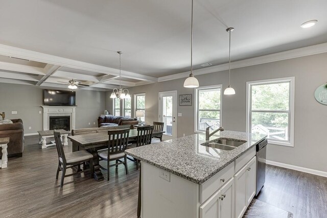 kitchen with dishwasher, a sink, baseboards, open floor plan, and a glass covered fireplace
