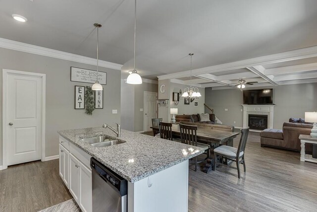 kitchen featuring a sink, a fireplace, baseboards, stainless steel dishwasher, and dark wood-style floors