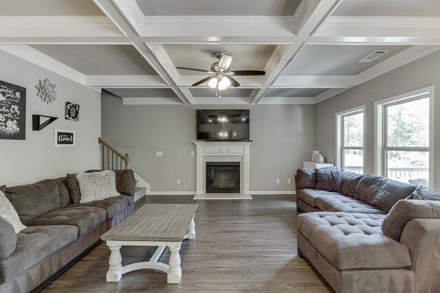 living area featuring visible vents, dark wood-style flooring, a glass covered fireplace, beamed ceiling, and a ceiling fan