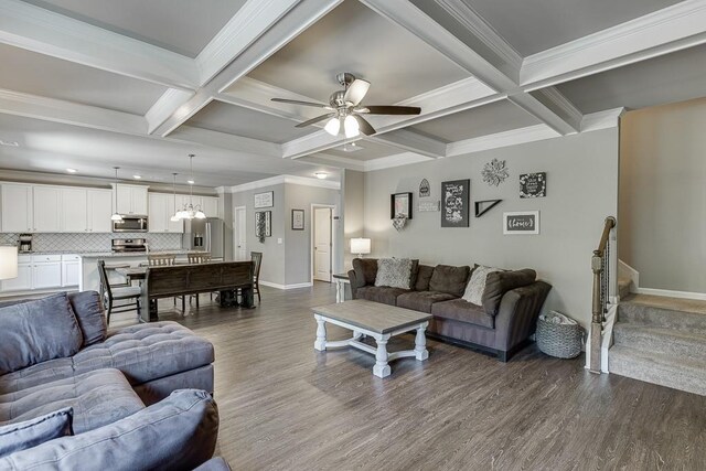 living room featuring dark wood-type flooring, baseboards, ceiling fan with notable chandelier, and beam ceiling