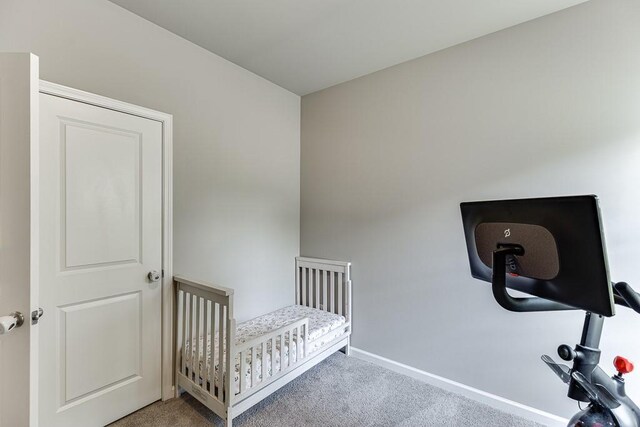 carpeted bedroom with baseboards and a crib