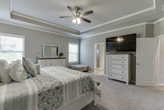 bedroom featuring visible vents, crown molding, a tray ceiling, and light carpet