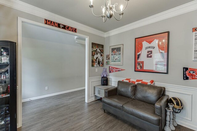 living area with ornamental molding, wood finished floors, and a chandelier