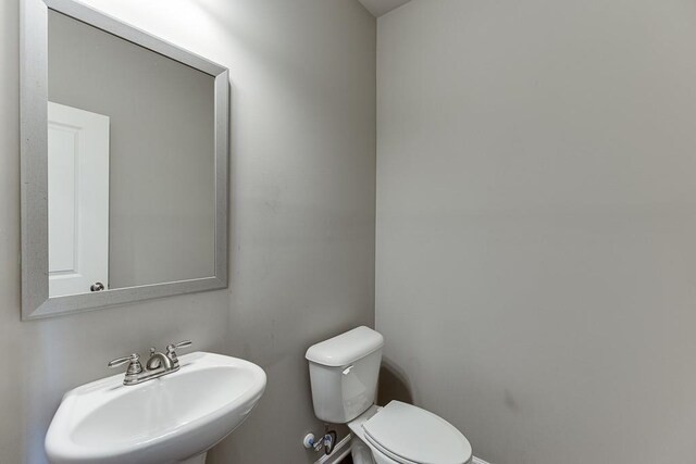 half bath featuring baseboards, a sink, and toilet