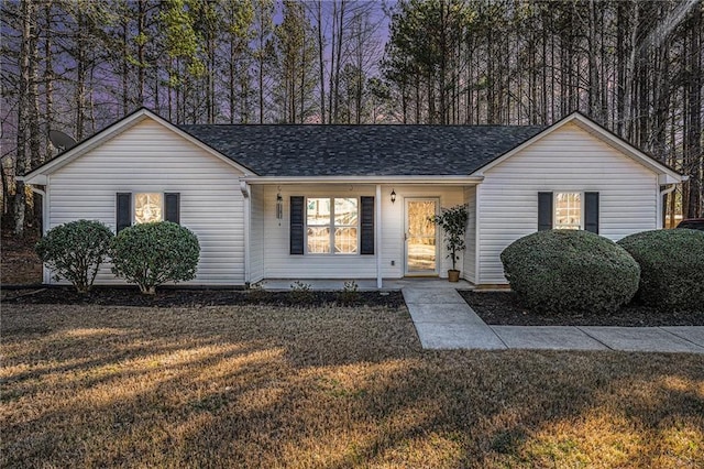 ranch-style home with a front lawn and roof with shingles