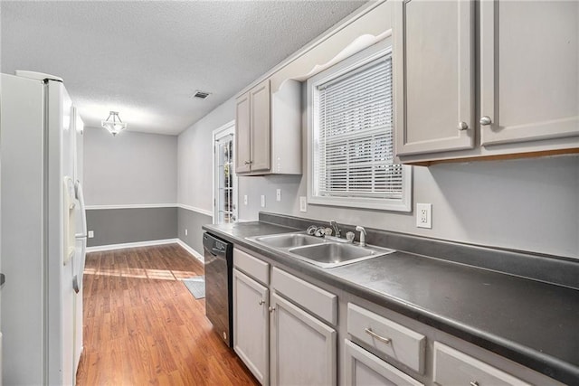 kitchen with black dishwasher, dark countertops, gray cabinets, freestanding refrigerator, and a sink