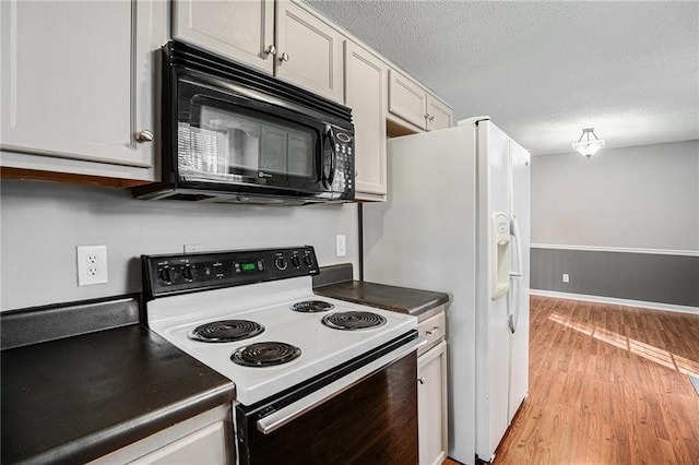 kitchen with dark countertops, electric range, light wood-style floors, white cabinetry, and black microwave