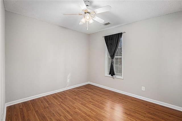 unfurnished room with a ceiling fan, baseboards, visible vents, and wood finished floors