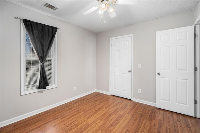 unfurnished bedroom featuring baseboards, visible vents, a ceiling fan, wood finished floors, and a textured ceiling