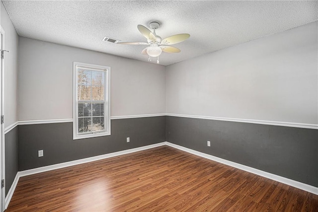 spare room featuring wood finished floors, visible vents, and baseboards