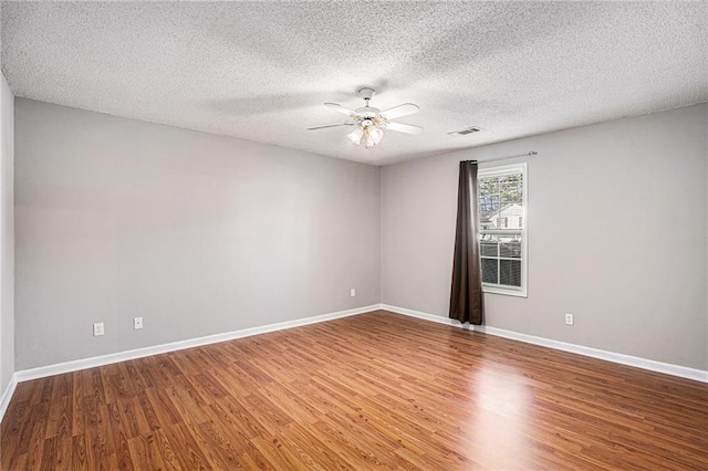 spare room with ceiling fan, a textured ceiling, wood finished floors, and baseboards