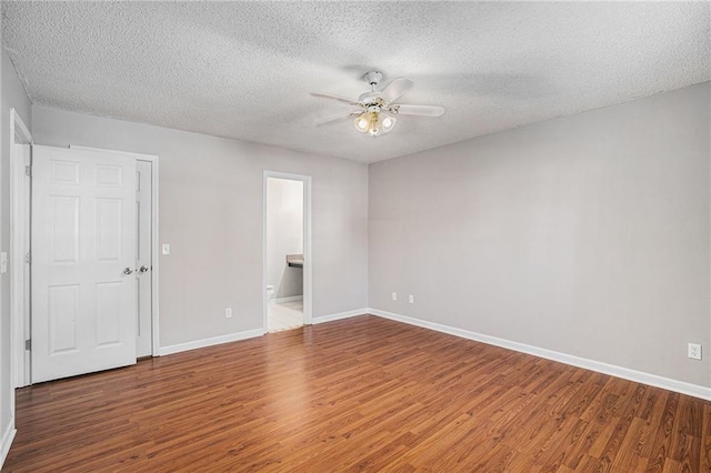 empty room with ceiling fan, a textured ceiling, baseboards, and wood finished floors