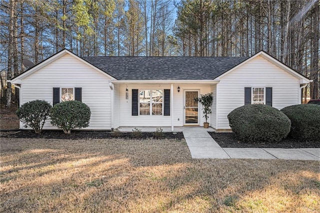 single story home featuring a front lawn and roof with shingles