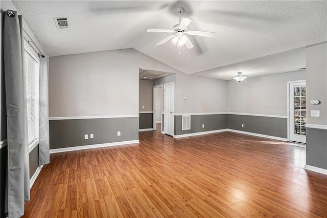 spare room featuring lofted ceiling, a ceiling fan, visible vents, and wood finished floors