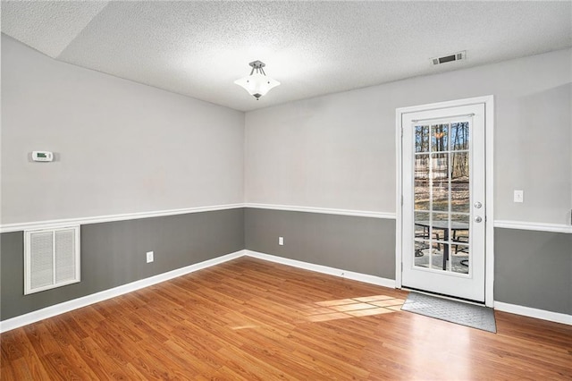 empty room with visible vents, baseboards, and wood finished floors