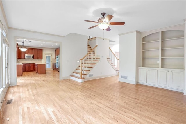 unfurnished living room featuring ceiling fan, built in shelves, crown molding, and light hardwood / wood-style flooring