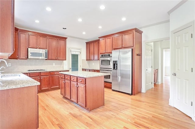 kitchen featuring decorative backsplash, a kitchen island, light hardwood / wood-style floors, and stainless steel appliances