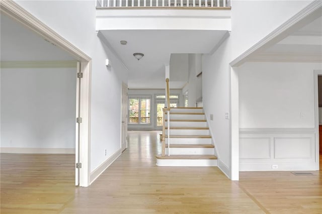 staircase featuring a high ceiling, hardwood / wood-style flooring, and ornamental molding