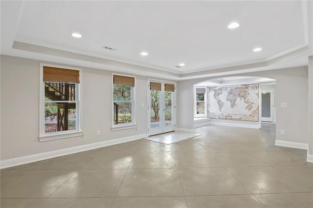 empty room featuring french doors, a tray ceiling, light tile patterned floors, and ornamental molding