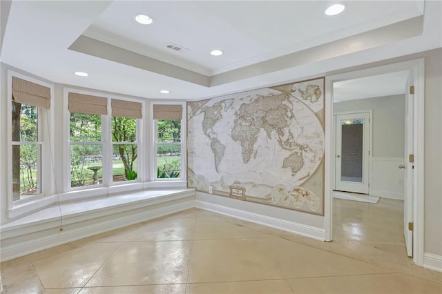 tiled spare room with a tray ceiling and ornamental molding