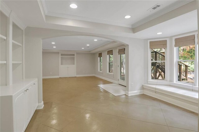 interior space with a tray ceiling, a wealth of natural light, and crown molding